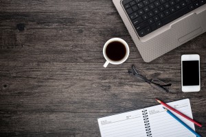 Escritorio con cafe, teléfono, laptop, y libreta